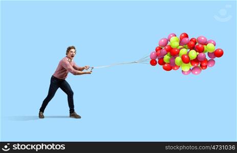 Man with balloons. Young man in casual with bunch of colorful balloons