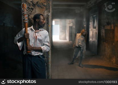 Man with baseball bat prepares to kill zombie, deadly chase in abandoned factory. Horror in city, creepy crawlies attack, doomsday apocalypse, bloody monster