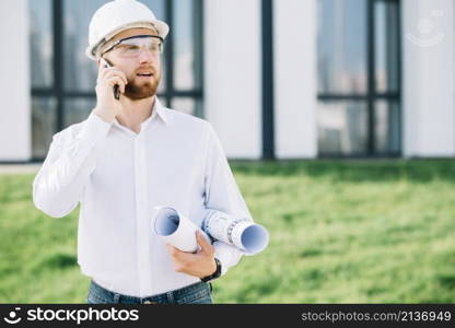 man with blueprints talking phone