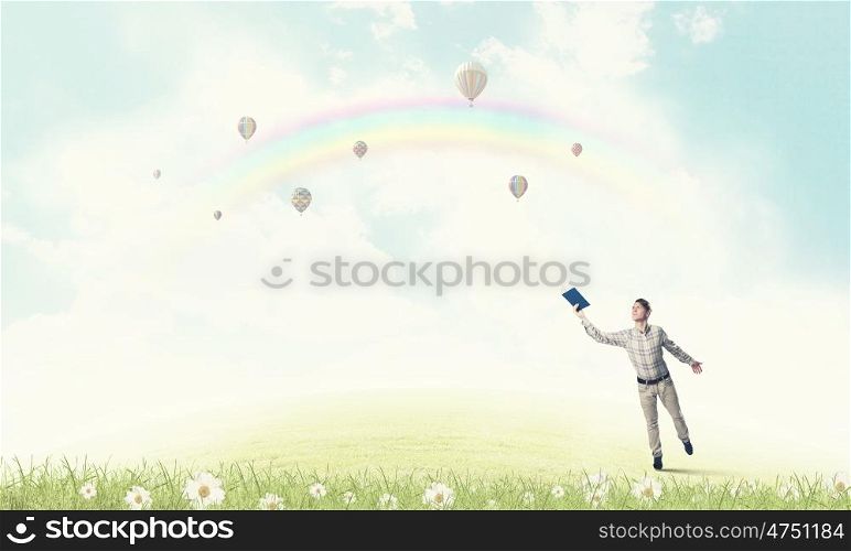 Man with book in hand. Young handsome man on sky background reaching hand with book