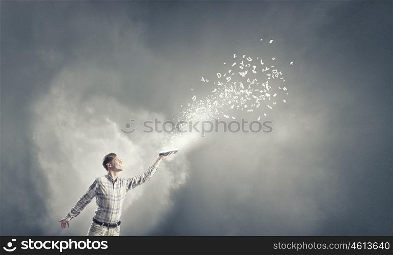 Man with book in hand. Young handsome man reaching hand with book and characters flying out