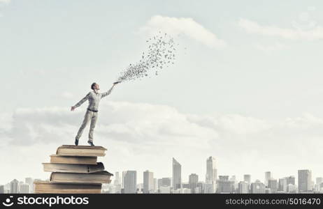 Man with book in hand. Young handsome man reaching hand with book and characters flying out