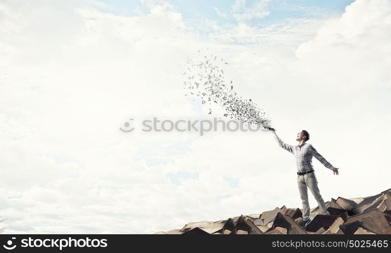 Man with book in hand. Young handsome man reaching hand with book and characters flying out