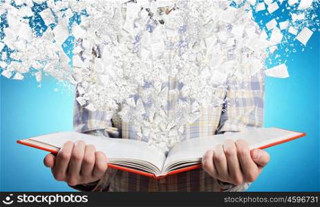Man with book on dark background. Young man with opened book in hands and pages flying in air