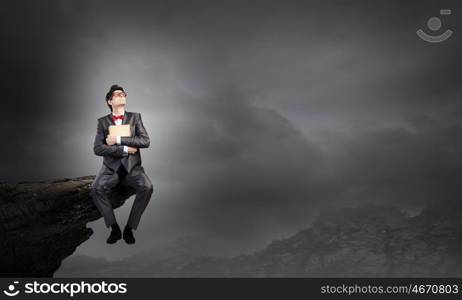 Man with book. Young businessman with book in hands sitting on top