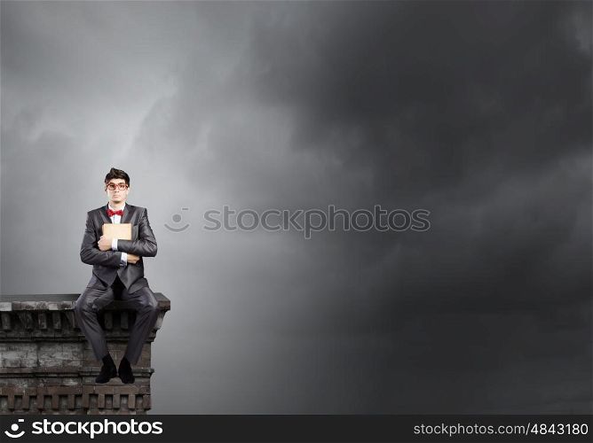 Man with book. Young businessman with book in hands sitting on top