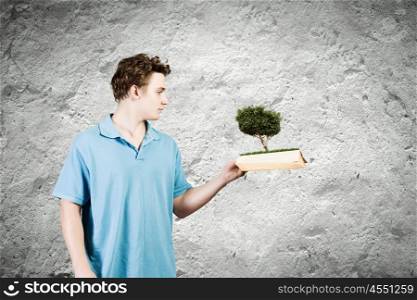 Man with book. Young man in casual holding opened book with green tree