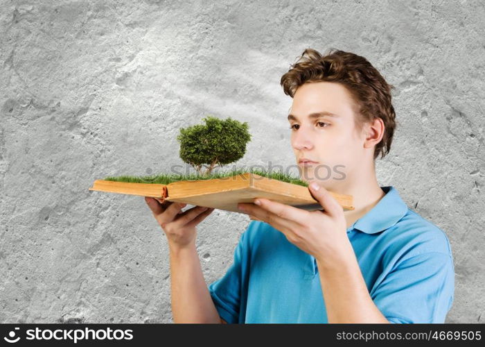 Man with book. Young man in casual holding opened book with green tree