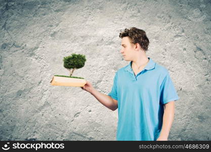 Man with book. Young man in casual holding opened book with green tree