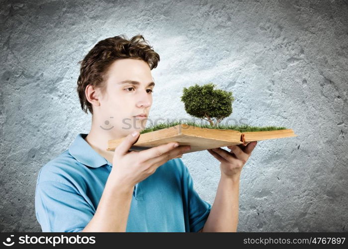 Man with book. Young man in casual holding opened book with green tree