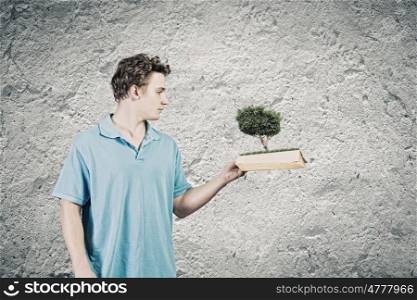 Man with book. Young man in casual holding opened book with green tree