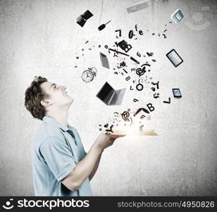 Man with book. Young man in casual holding opened book with icons flying out