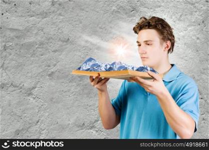 Man with book. Young man in casual holding opened book with mountain landscape
