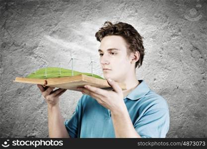 Man with book. Young man in casual holding opened book with windmills