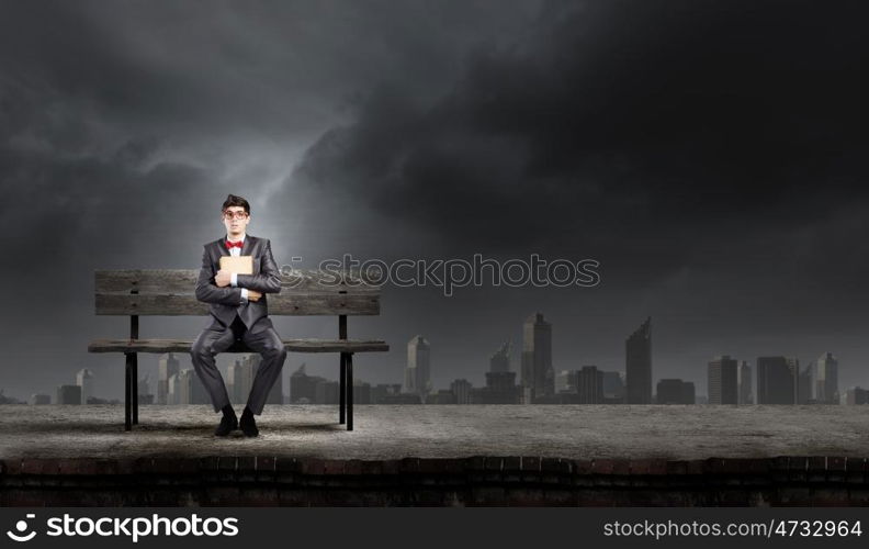 Man with book. Young man in suit sitting on bench with book in hands