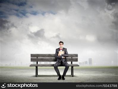 Man with book. Young man in suit sitting on bench with book in hands