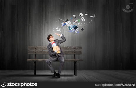 Man with book. Young man in suit sitting on bench with book in hands