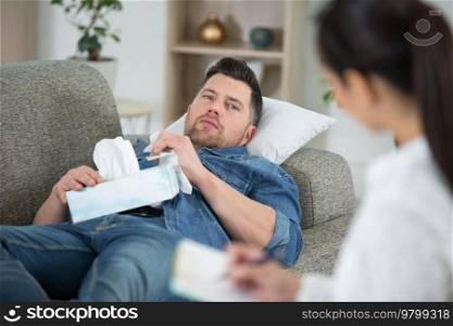 man with box of tissues talking to a counsellor