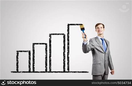 Man with brush. Young businessman painting graphs and diagrams with brush