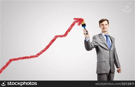 Man with brush. Young businessman painting growing arrow with brush