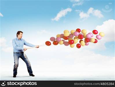 Man with bunch of balloons. Image of adult man holding bunch of colorful balloons