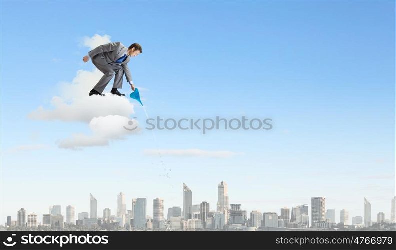 Man with can. Young businessman standing on cloud and watering something below