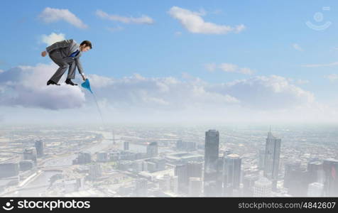 Man with can. Young businessman standing on cloud and watering something below