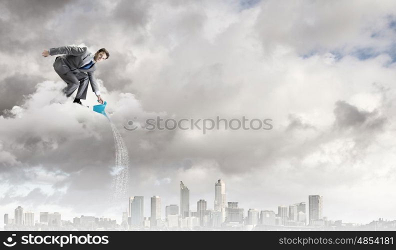 Man with can. Young businessman standing on cloud and watering something below