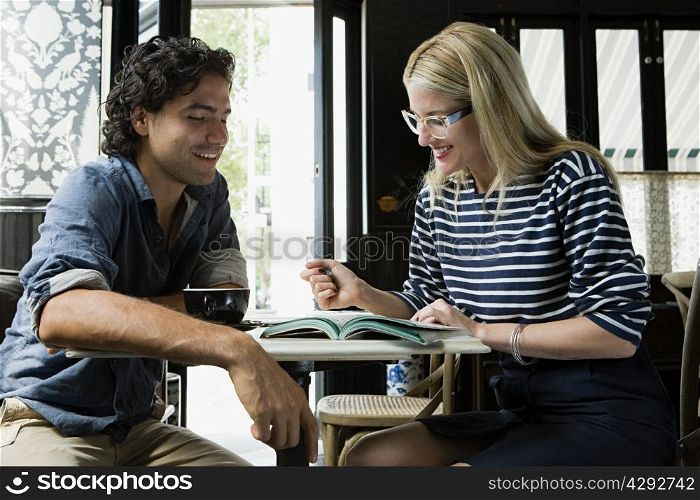 Man with cellphone and woman with laptop in cafe