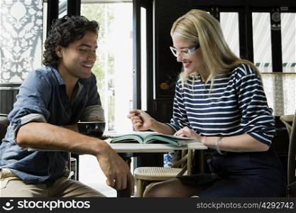 Man with cellphone and woman with laptop in cafe
