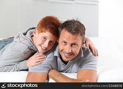 Man with child lying on a sofa at home