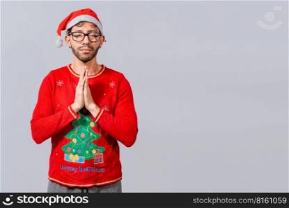 Man with christmas hat with praying hands isolated. Guy with hands together praying in christmas isolated, concept of person with christmas hat praying and making a wish