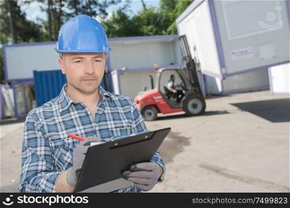 Man with clipboard controlling transport of cabins