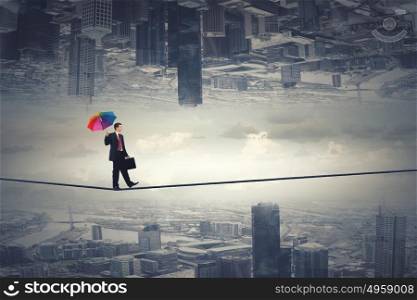 Man with colorful umbrella. Businessman with colorful umbrella and suitcase walking on rope