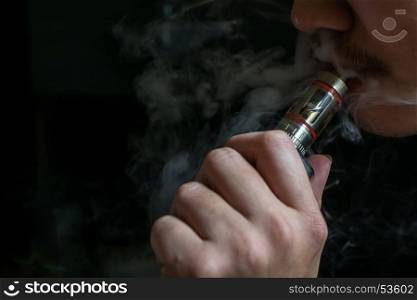 Man with concealed identity smoking a controversial vaping an electronic cigarette. Vaping is debatable in the health community if it is safe or a health risk