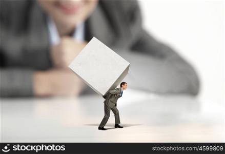 Man with cube. Businesswoman looking at miniature of man carrying white cube on back