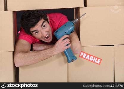 Man with drill amongst boxes