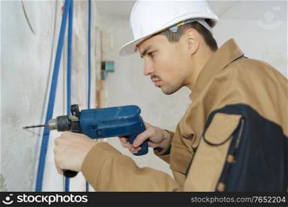 man with drill or screwdriver and construction helmet