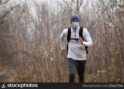 man with face mask running woods