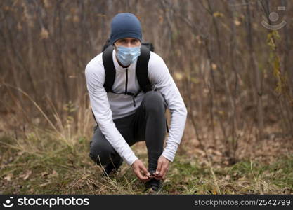 man with face mask woods tying shoelaces