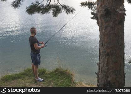 Man with fishhook in front of mountain dam. Bulgaria