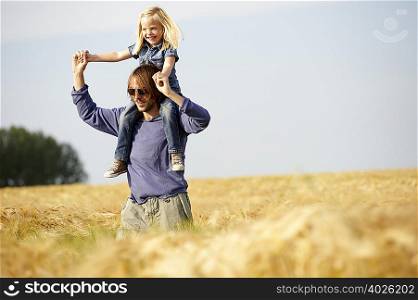 Man with girl on shoulders in a field