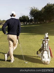 man with golf clubs field