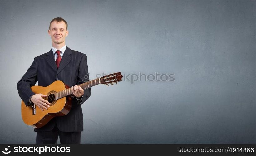 Man with guitar. Young man in black suit playing acoustic guitar