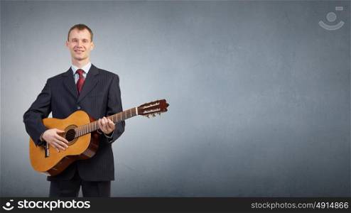 Man with guitar. Young man in black suit playing acoustic guitar