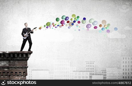 Man with guitar. Young man in black suit playing electric guitar