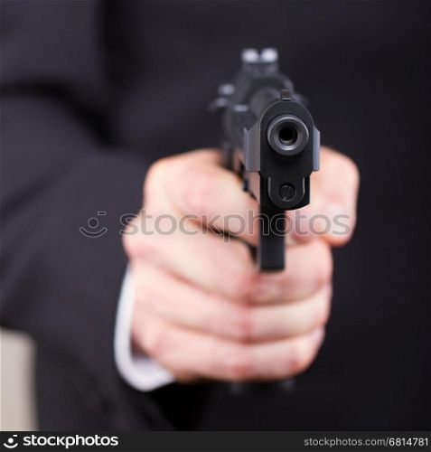 Man with gun, business suit, focus on the gun
