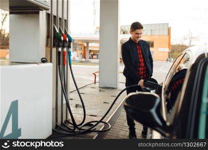Man with gun fuels vehicle on gas station, fuel filling. Petrol fueling, gasoline or diesel refuel service. Man with gun fuels vehicle on gas station