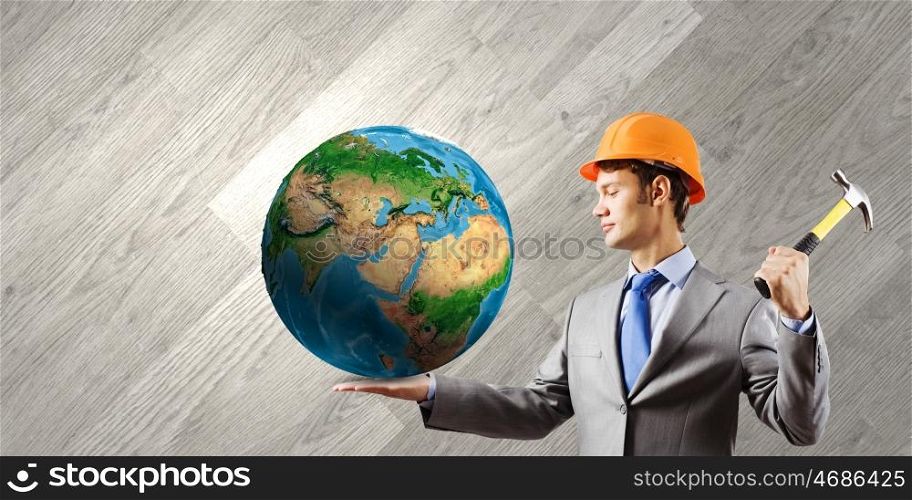 Man with hammer. Businessman in helmet hammering nail in Earth planet. Elements of this image are furnished by NASA
