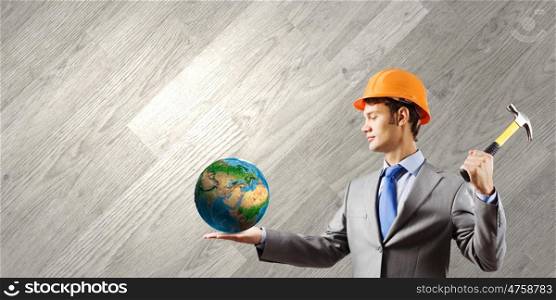 Man with hammer. Businessman in helmet hammering nail in Earth planet. Elements of this image are furnished by NASA